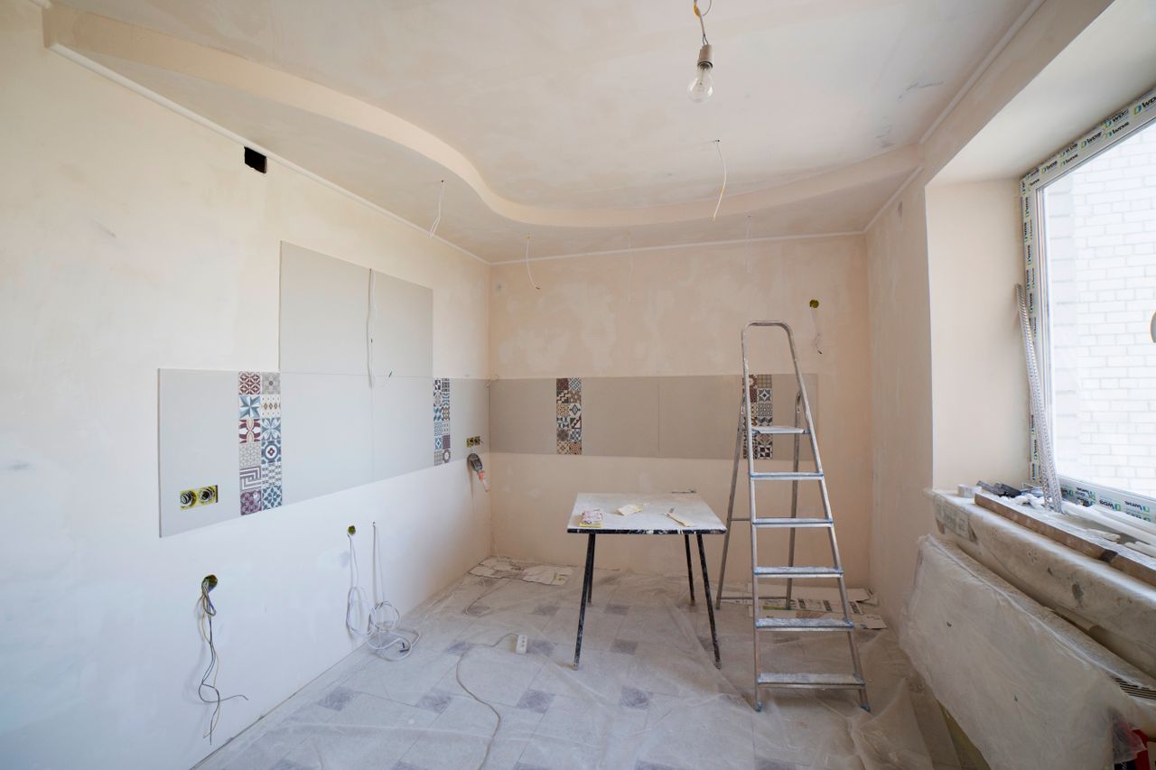 our-story-01 Spacious kitchen under renovation with ladder and tools, showcasing a fresh new design.